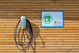 Wall-mounted Tesla charger next to an EV charging sign on a wooden wall; illustrative installation
