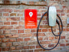 Tesla Gen 2 Wall Connector mounted on a brick wall with Tesla vehicle charging sign